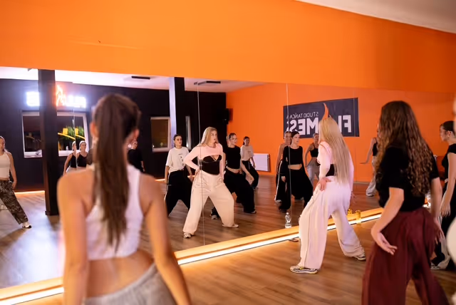 Tancerki ćwiczą choreografię przed lustrem w sali Studia Tańca Flames