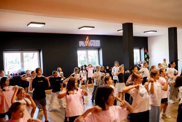 Duża grupa dzieci powtarza ruchy taneczne za instruktorką