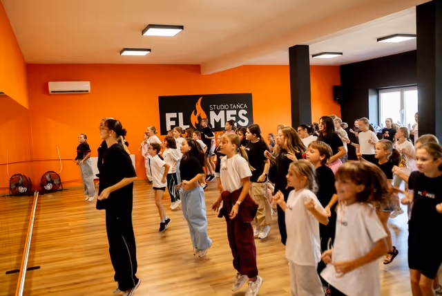 Dzieci i młodzież tańczą choreografię pod logo Studia Tańca Flames