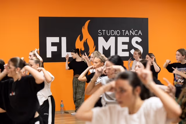 Tancerki wykonują ruch rąk przy twarzy podczas nauki choreografii